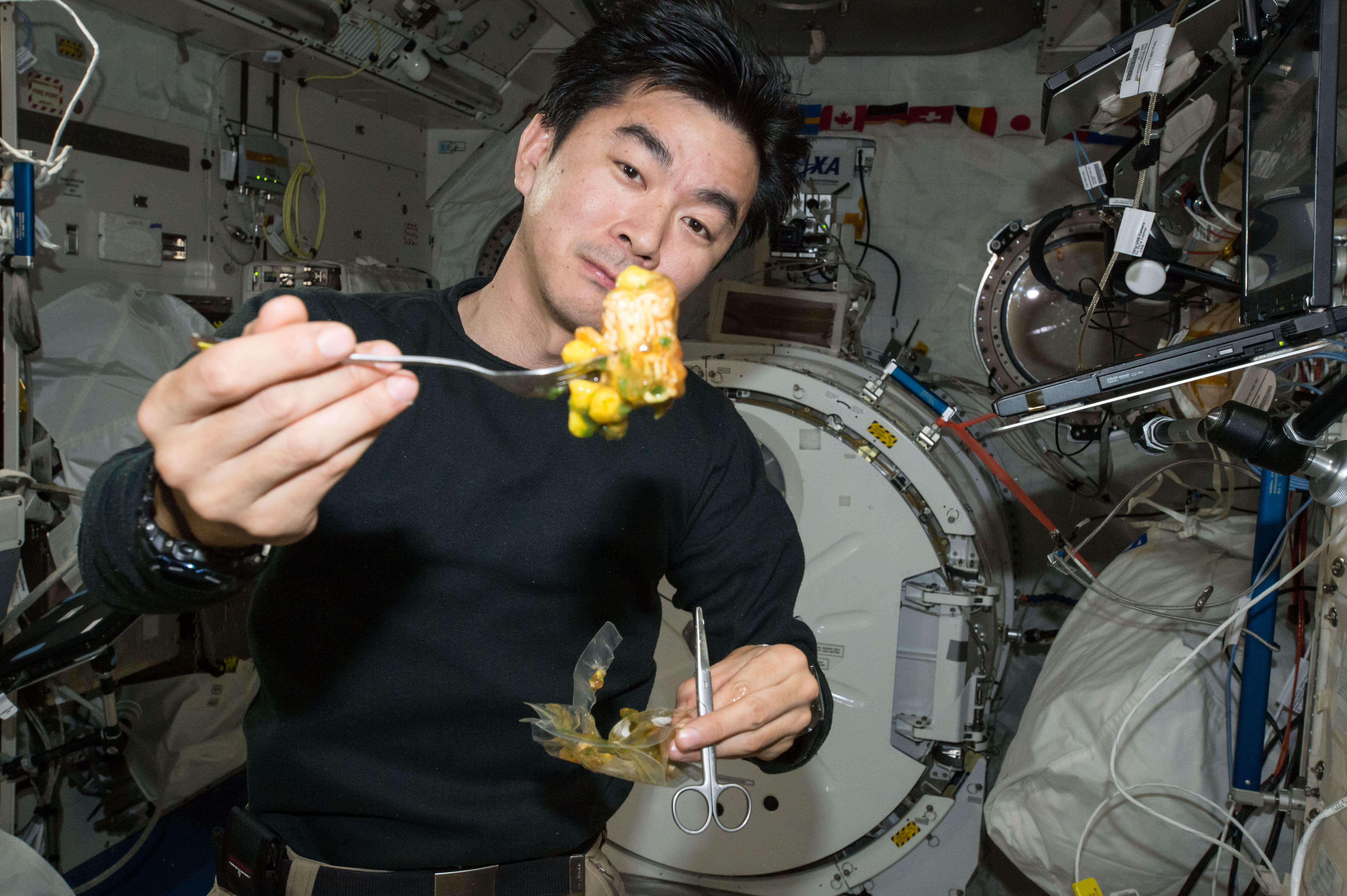 宇宙日本食のしょうゆラーメンを食べる油井宇宙飛行士。ラーメンは飛び散らないように粘性を高めている。
