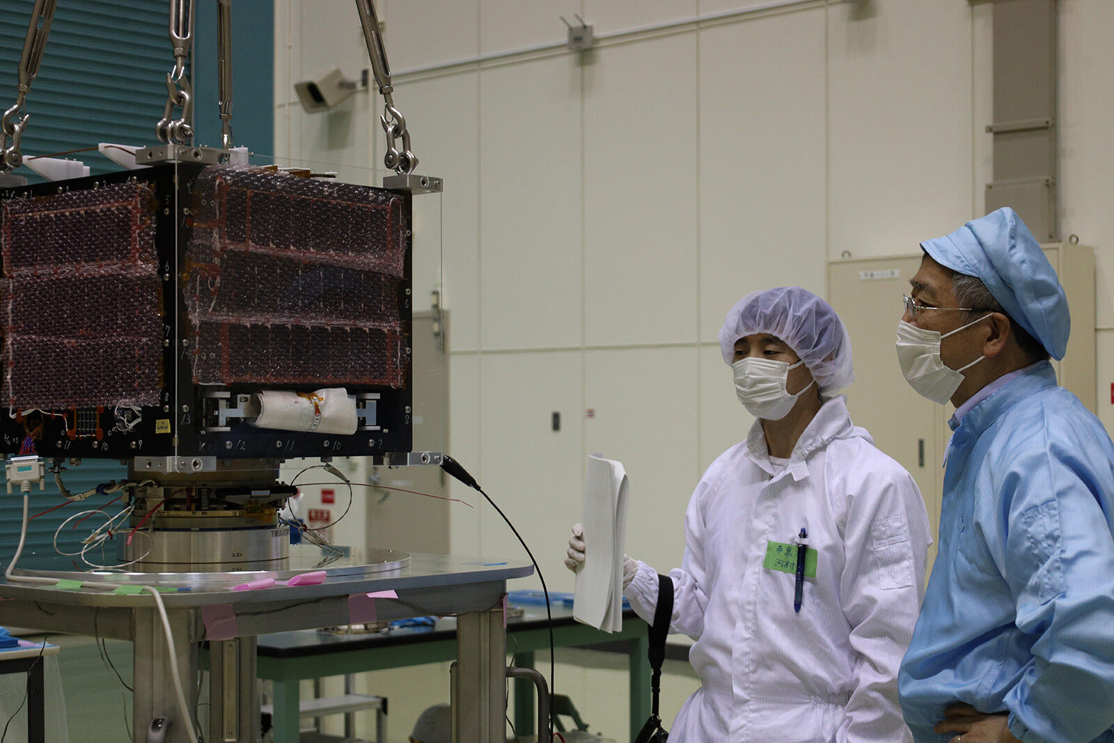 今回搭載される超小型衛星の1つ、TeikyoSat-4の試験に立ち会う金子グループ長（写真右）。